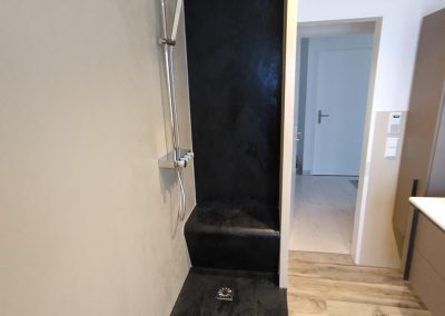 Fugenlose Dusche in dunkler Steinoptik mit gemauerter Sitzbank